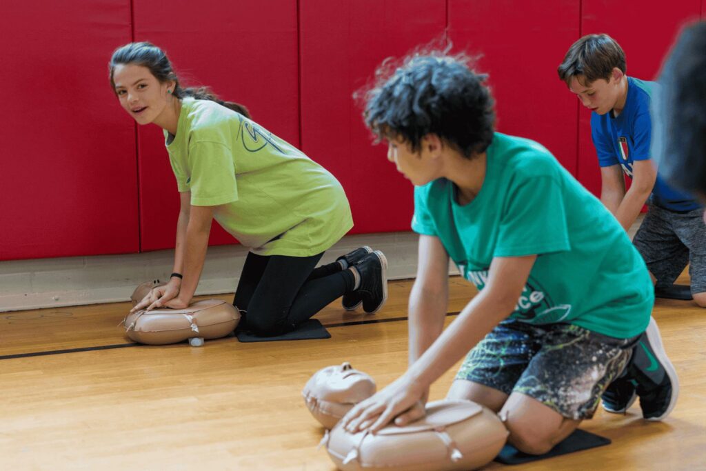 Students learning hands‑only CPR using manikins during school training